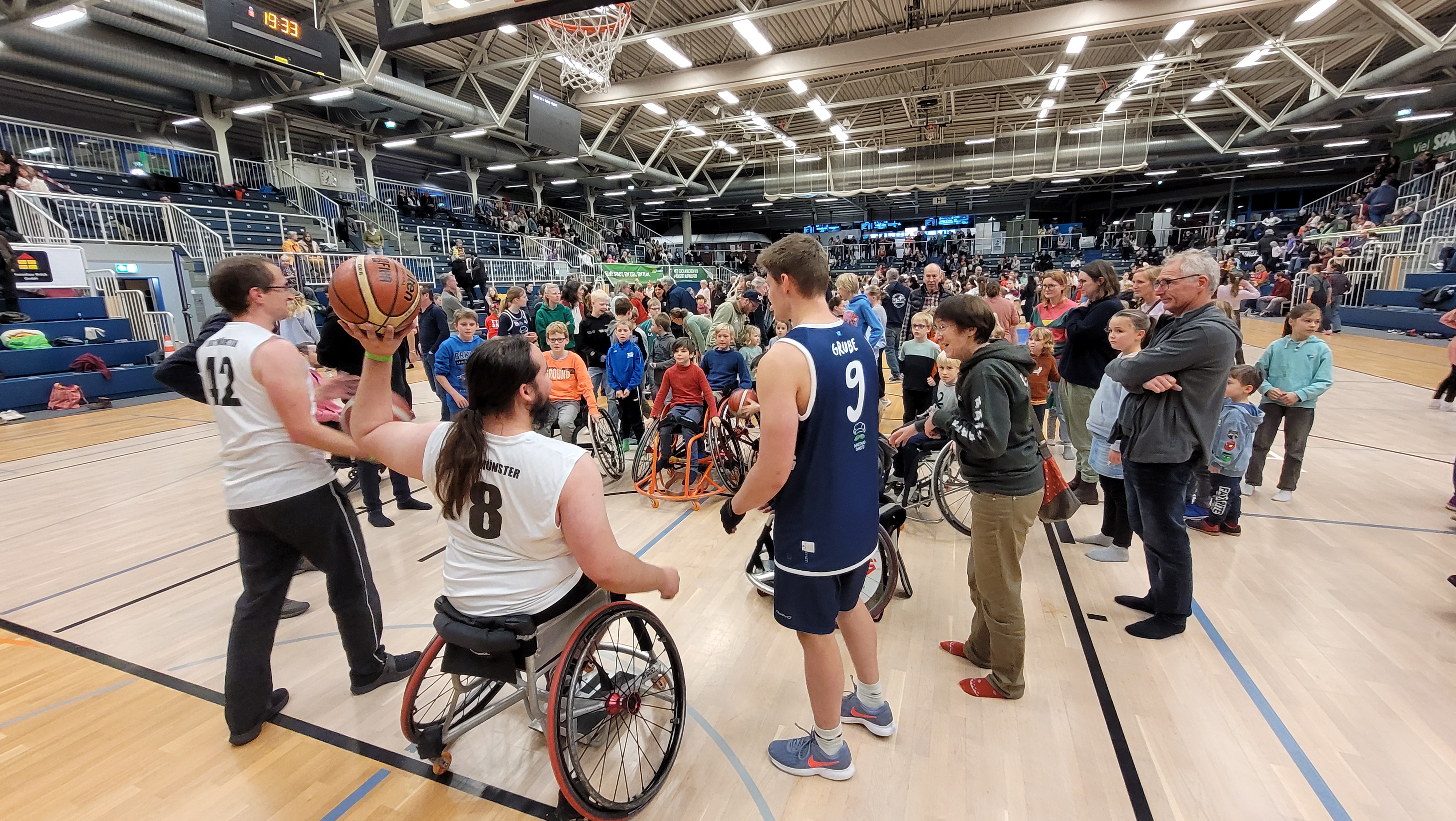 eine Gruppe von Kindern in Rollstühlen wartet darauf, dass ihnen ein Rollstuhl-Basketballspieler den Ball von der Grundlinie aus zuwirft wirft eine Gruppe von Kindern in Rollstühlen wartet darauf, dass ihnen ein Rollstuhl-Basketballspieler den Ball von der Grundlinie zuwirft