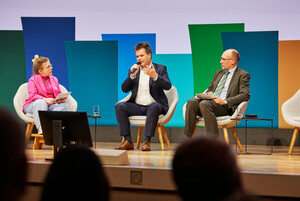 drei Personen sitzen auf dem Podium und diskutieren, Jürgen Dusel, die person in der Mitte spricht gerade und gestikuliert dabei 