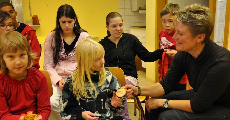 Kinder der Hans-Zulliger-Schule in Enkenbach-Alsenborn betrachten staunend die Goldmedaillen von Hannelore Brenner. Foto: Jochen Dick