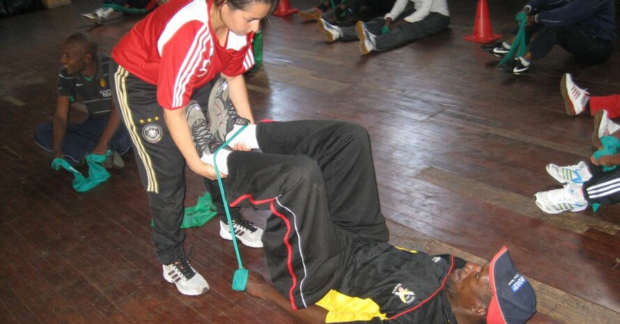 Laura Daras, Expertin für Stretching- und Krafttraining, zeigt einem simbabwischen Trainer die Arbeit mit dem Theraband. Foto: Pagels/DOSB