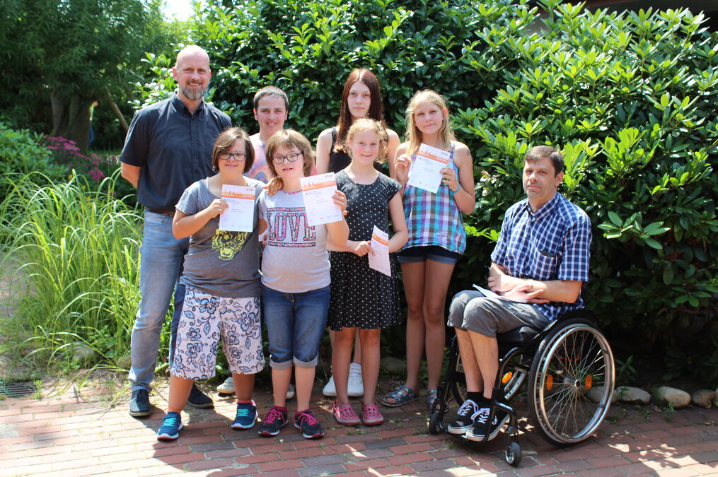 Gruppenfoto der zehn jungen Sportler/innen, die ihre Urkunden in den Händen halten, mit Stefan Doege (Sport-Inklusionsmanager der HpH) und Axel Wichmann (Schulleiter Paul-Moor-Schule). Gruppenfoto der zehn jungen Sportler/innen, die ihre Urkunden in den Händen halten, mit Stefan Doege (Sport-Inklusionsmanager der HpH) und Axel Wichmann (Schulleiter Paul-Moor-Schule).