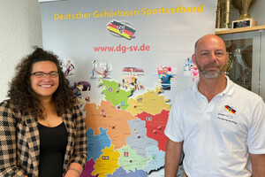 Zwei Personen stehen vor einem Schaubild des Deutschen Gehörlosen-Sportverbands
