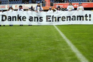Jugendliche halten vor dem Anppfiff eines Fußballspiels ein Banner mit der Aufschrift: "Danke ans Ehrenamt". Foto: picture-alliance