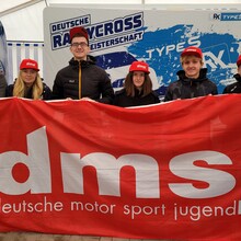 Acht Personen halten ein großes rotes Banner mit der Aufschrift dmsj deutsche motor sport jugend