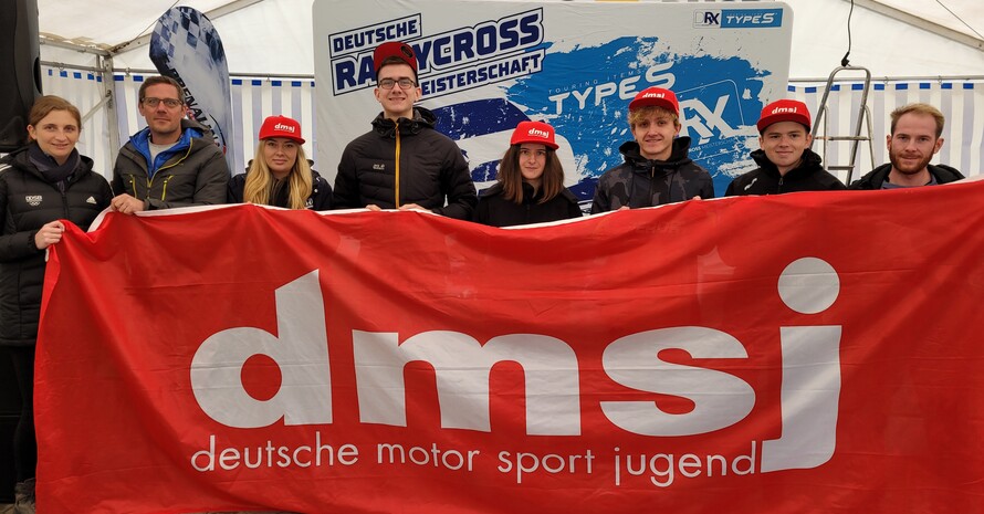 Acht Personen halten ein großes rotes Banner mit der Aufschrift dmsj deutsche motor sport jugend