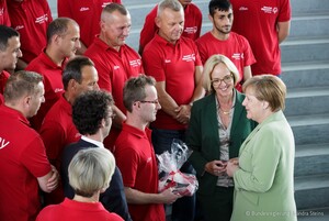 Leichtathlet Sebastian Kröger, Athletensprecher der Deutschen Delegation, überreichte Bundeskanzlerin Angela Merkel ein Delegationsbuch und ein T-Shirt als Gastgeschenk. Links neben der Kanzlerin steht SOD-Präsidentin Christiane Krajewski (Foto: Bundes